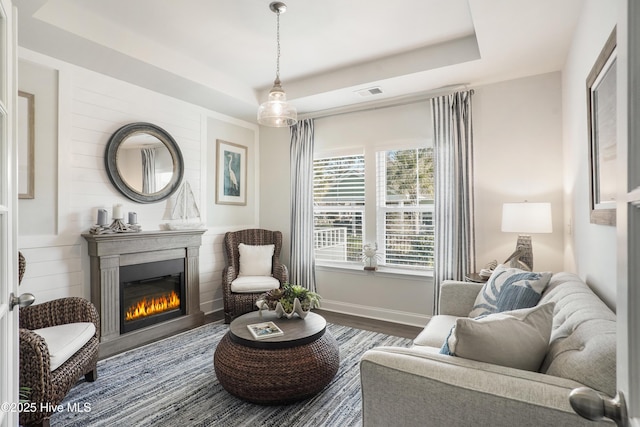 sitting room with a tray ceiling and hardwood / wood-style floors