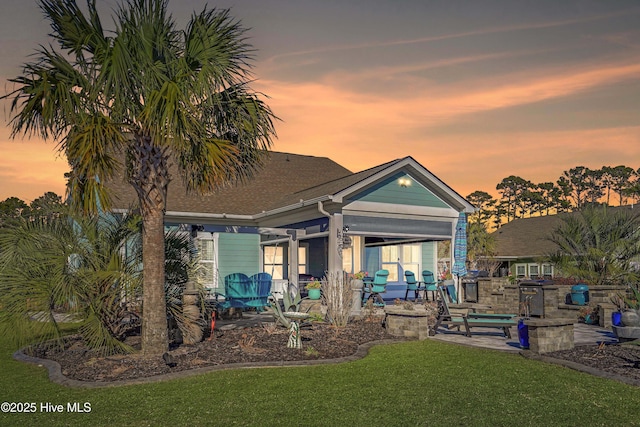 back house at dusk with a yard and a patio area