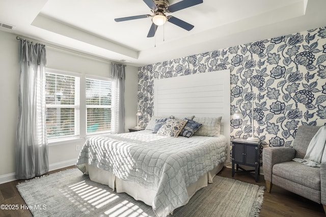 bedroom with a tray ceiling, dark hardwood / wood-style floors, and ceiling fan