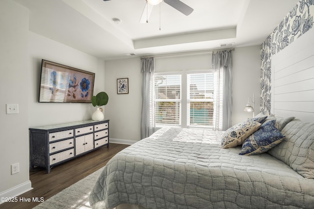 bedroom featuring a tray ceiling, dark wood-type flooring, and ceiling fan