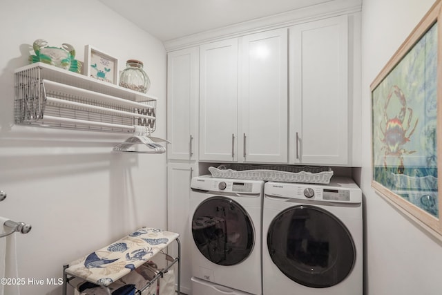 clothes washing area with cabinets and washer and clothes dryer