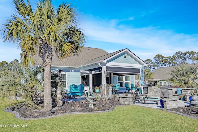 rear view of house with a patio area, a lawn, and an outdoor kitchen