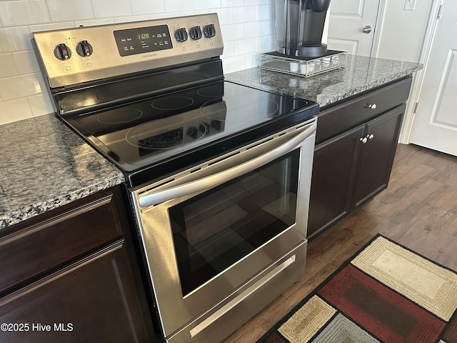 kitchen with stone countertops, dark brown cabinets, stainless steel electric range, dark hardwood / wood-style floors, and decorative backsplash