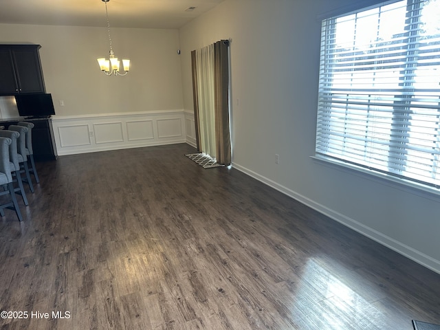 unfurnished dining area with dark hardwood / wood-style flooring and an inviting chandelier