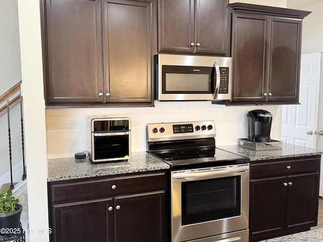 kitchen featuring appliances with stainless steel finishes, light stone countertops, and dark brown cabinets