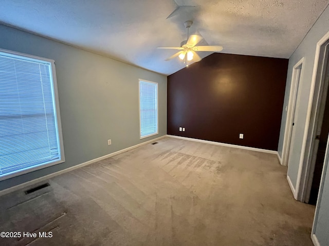 unfurnished bedroom with lofted ceiling, ceiling fan, light carpet, and a textured ceiling