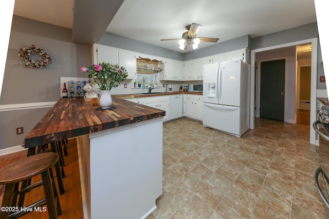 kitchen with sink, white cabinetry, white refrigerator with ice dispenser, wood counters, and kitchen peninsula