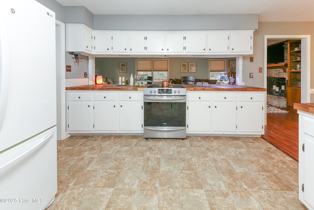 kitchen featuring stainless steel electric range oven, freestanding refrigerator, and white cabinetry