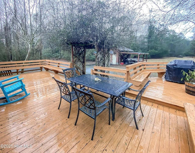 wooden terrace with outdoor dining space and a wooded view