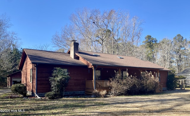 exterior space with covered porch, roof with shingles, a front lawn, and a chimney