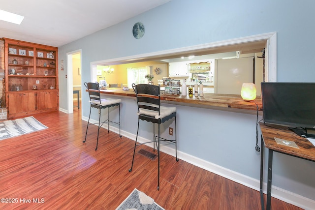 kitchen with white cabinetry, light hardwood / wood-style floors, a kitchen breakfast bar, and kitchen peninsula