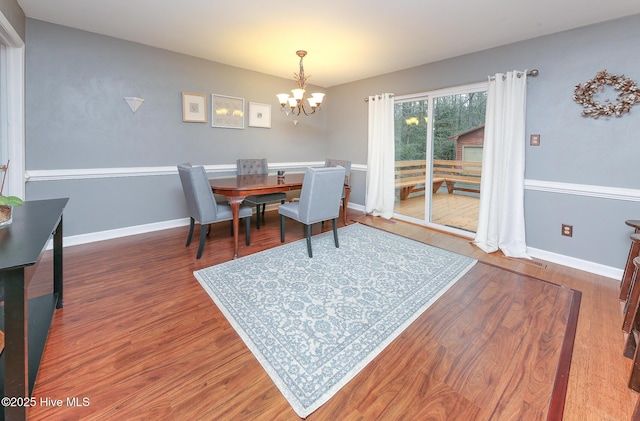 dining space with a chandelier, baseboards, and wood finished floors