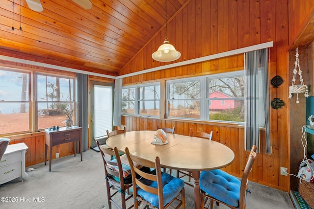 carpeted dining area featuring wood ceiling, wooden walls, and vaulted ceiling