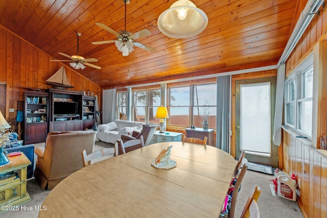 dining area featuring light colored carpet, lofted ceiling, wooden ceiling, and wood walls