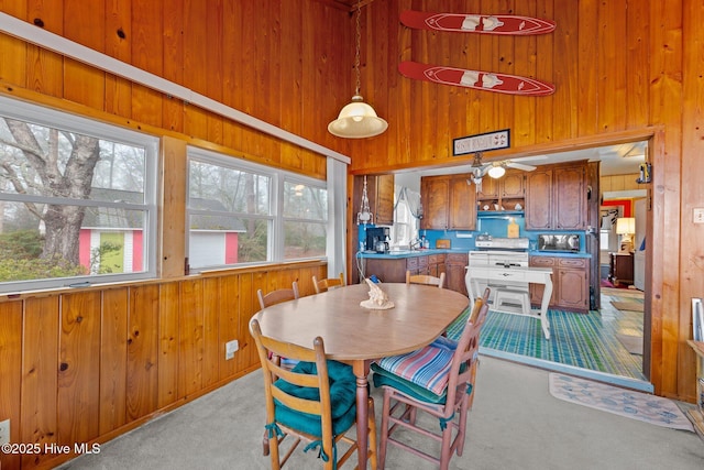 carpeted dining area featuring a towering ceiling and wood walls