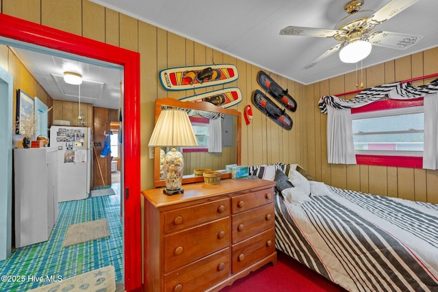 bedroom featuring ceiling fan, white fridge, and wood walls