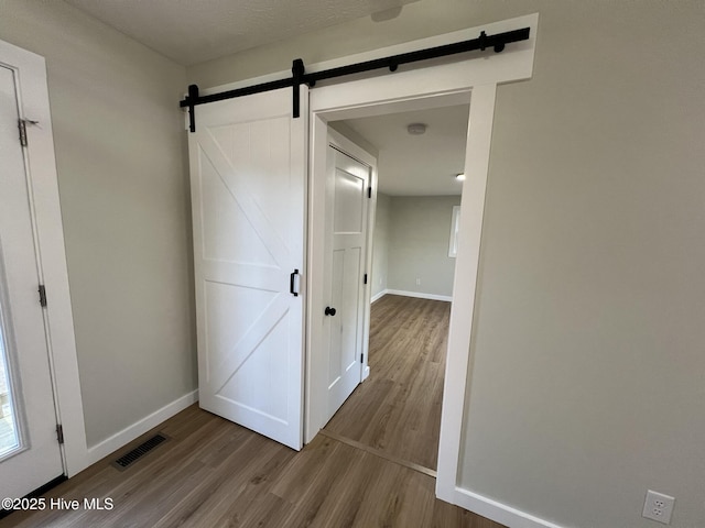 hallway featuring a barn door and light hardwood / wood-style flooring