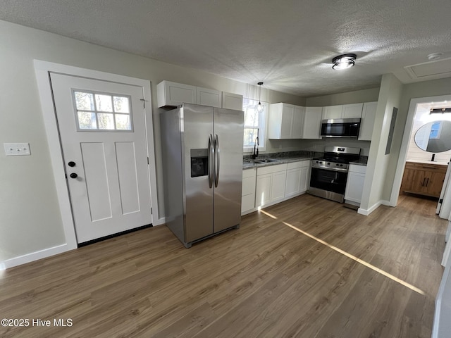 kitchen with sink, dark wood-type flooring, white cabinets, and appliances with stainless steel finishes