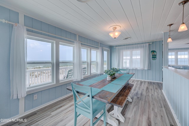 dining space featuring a water view, wood ceiling, and light hardwood / wood-style floors