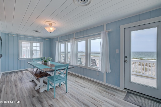 dining room with light wood-type flooring, wooden ceiling, and a water view