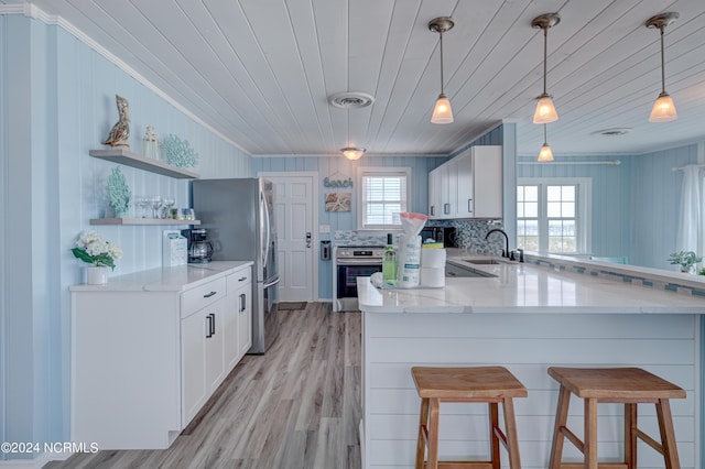 kitchen featuring white cabinetry, oven, kitchen peninsula, and stainless steel refrigerator