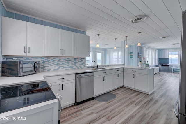 kitchen featuring white cabinetry, stainless steel appliances, decorative light fixtures, and kitchen peninsula