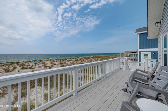 wooden deck with a water view and a beach view