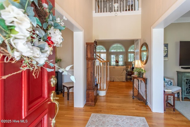 entryway with a towering ceiling, light hardwood / wood-style flooring, and french doors