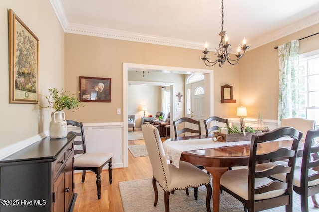 dining space featuring crown molding, a notable chandelier, and light hardwood / wood-style flooring