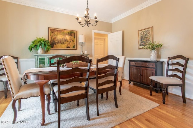 dining space with crown molding, a chandelier, and light hardwood / wood-style floors