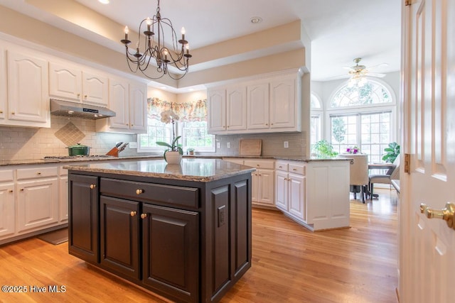 kitchen with hanging light fixtures, a center island, white cabinets, and light wood-type flooring