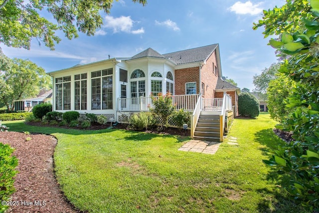 back of house with a sunroom, a deck, and a lawn