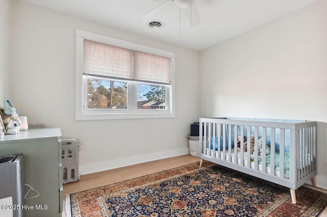 bedroom featuring wood-type flooring and a crib