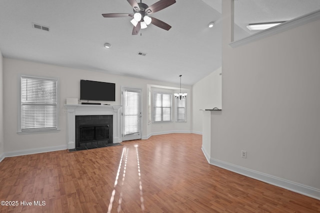 unfurnished living room featuring hardwood / wood-style floors and ceiling fan with notable chandelier