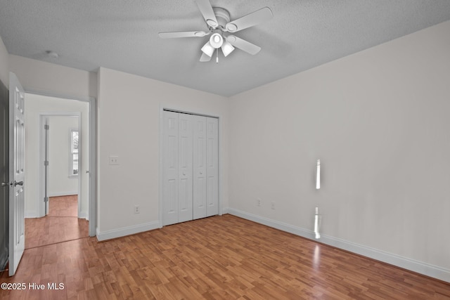 unfurnished bedroom featuring ceiling fan, a closet, light hardwood / wood-style floors, and a textured ceiling