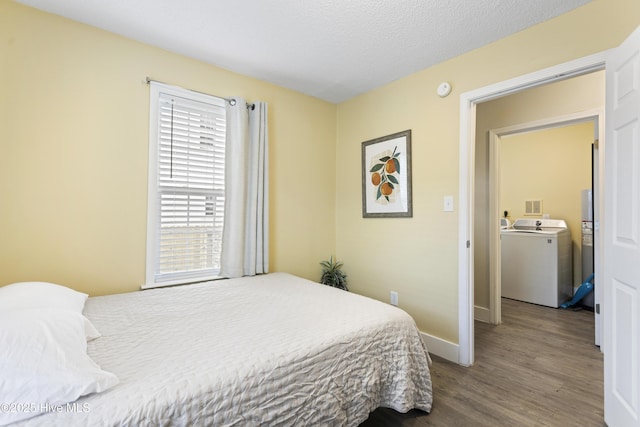 bedroom with hardwood / wood-style flooring, washer / dryer, and a textured ceiling