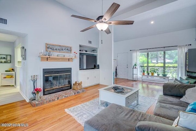 living room featuring hardwood / wood-style flooring, ceiling fan, a fireplace, and high vaulted ceiling