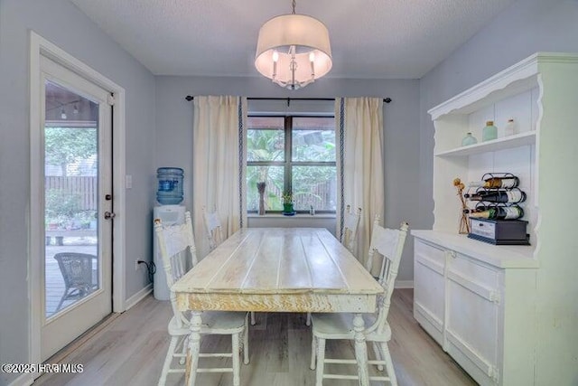 dining space with light hardwood / wood-style floors, a chandelier, and a healthy amount of sunlight