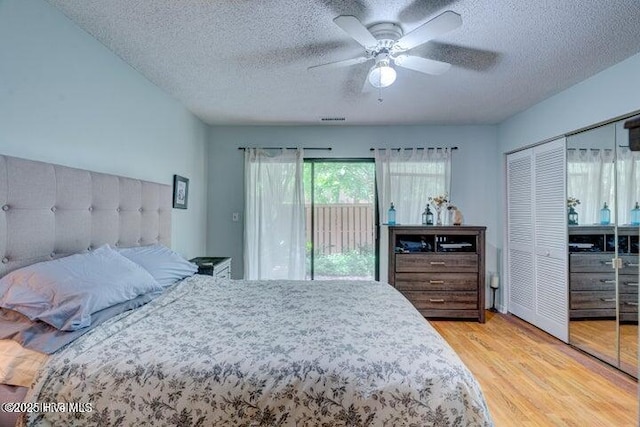 bedroom with a textured ceiling, light wood-type flooring, access to outside, a closet, and ceiling fan