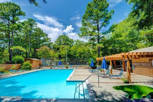 view of swimming pool with a storage shed, a patio, and a pergola