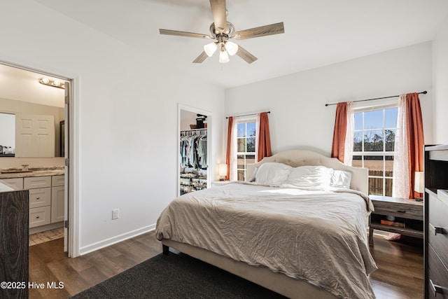 bedroom featuring a spacious closet, ceiling fan, dark wood-type flooring, ensuite bath, and a closet