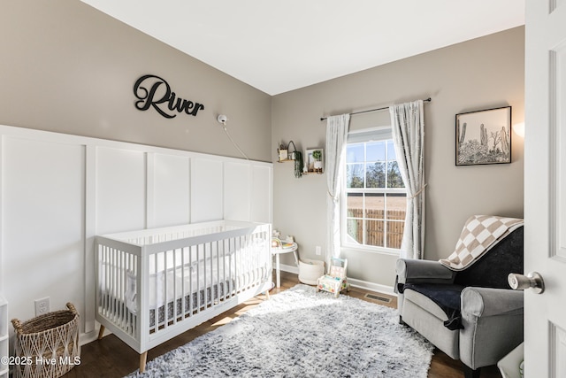 bedroom featuring dark hardwood / wood-style floors and a nursery area