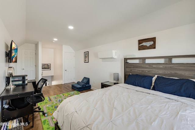 bedroom with lofted ceiling, hardwood / wood-style floors, and a wall unit AC