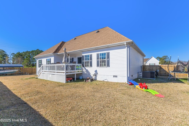 rear view of house with a wooden deck, a yard, central AC, and a trampoline