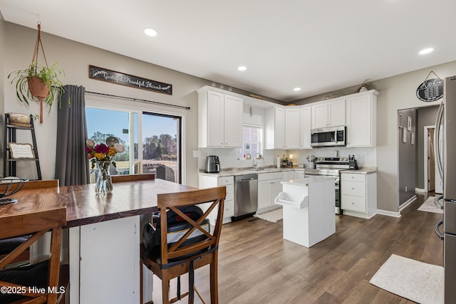 kitchen featuring a kitchen island, appliances with stainless steel finishes, dark wood-type flooring, and white cabinets