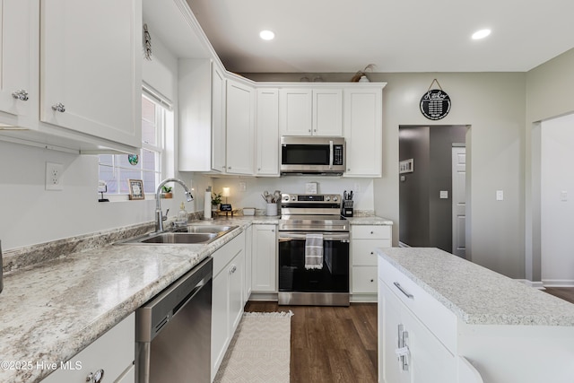 kitchen featuring sink, dark hardwood / wood-style flooring, stainless steel appliances, light stone countertops, and white cabinets