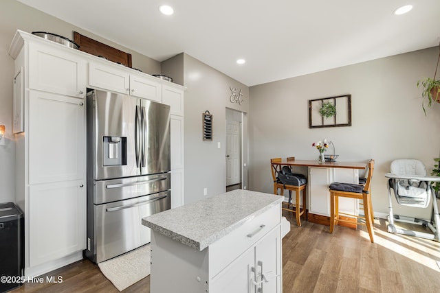 kitchen with white cabinetry, light hardwood / wood-style floors, a center island, and stainless steel refrigerator with ice dispenser