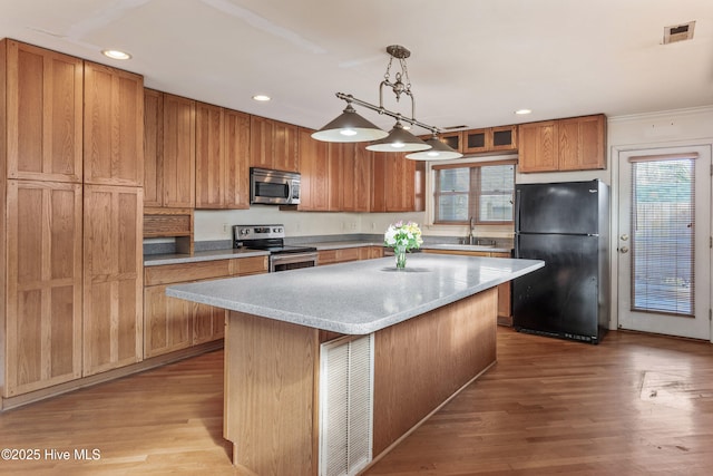 kitchen featuring light wood finished floors, visible vents, a center island, stainless steel appliances, and pendant lighting