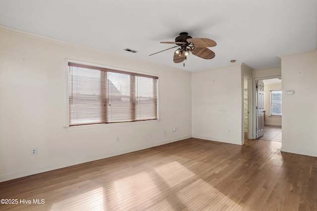 spare room with baseboards, visible vents, wood finished floors, and ornamental molding