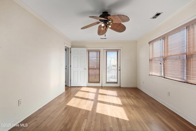 empty room with ceiling fan, visible vents, baseboards, light wood-style floors, and ornamental molding